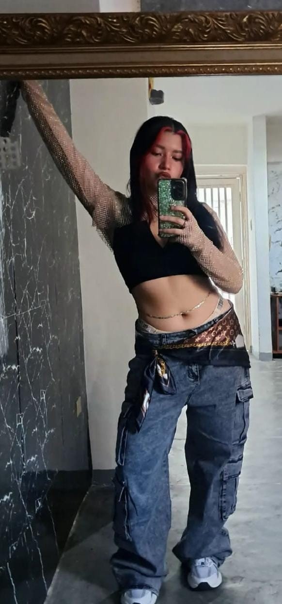 AYDI frente a un espejo con estilismo urbano y una pose con el brazo elevado.