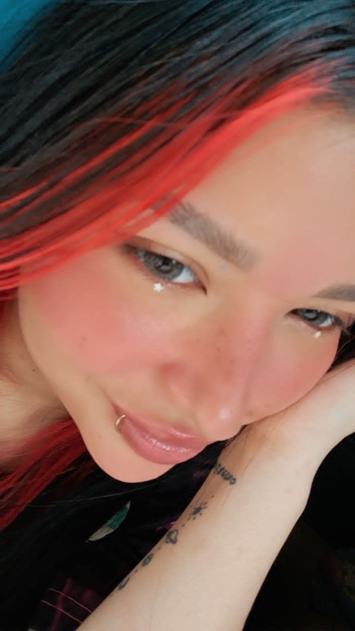 Primer plano de AYDI con cabello oscuro y rojo y maquillaje artístico.
